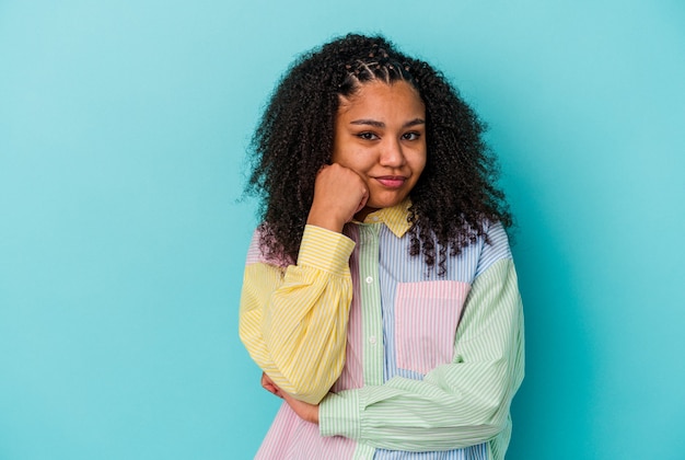 Jovem mulher afro-americana isolada em um fundo azul que se sente triste e pensativa, olhando para o espaço da cópia.