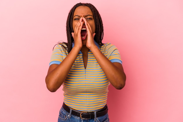 Jovem mulher afro-americana isolada em um fundo rosa gritando animado para a frente.