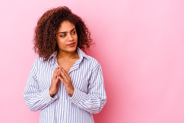 Jovem mulher afro-americana isolada em um fundo rosa, inventando o plano em mente, criando uma ideia.