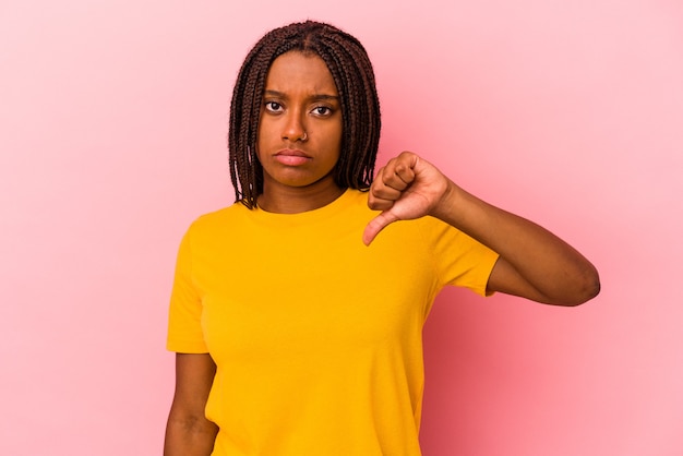 Jovem mulher afro-americana isolada em um fundo rosa, mostrando um gesto de antipatia, polegares para baixo. Conceito de desacordo.