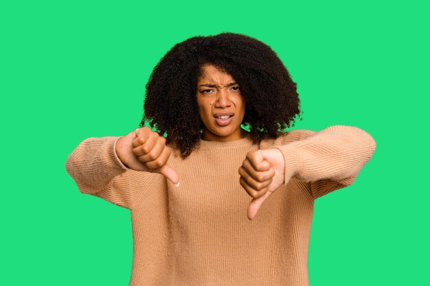 Jovem mulher afro-americana isolada mostrando o polegar para baixo e expressando aversão