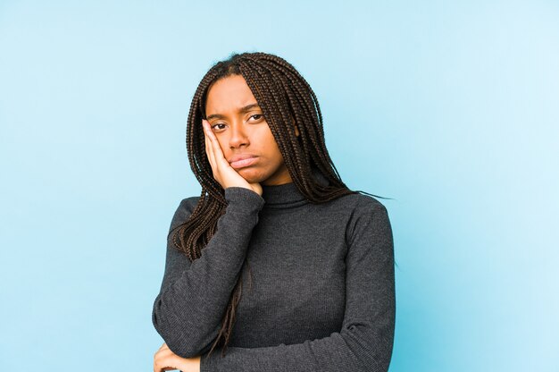 Jovem mulher afro-americana isolada na parede azul que está entediada, cansada e precisa de um dia de relaxamento.