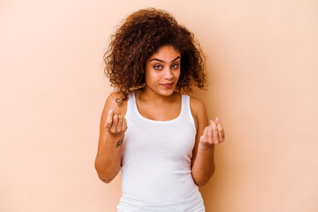 Jovem mulher afro-americana isolada na parede bege, mostrando que ela não tem dinheiro.