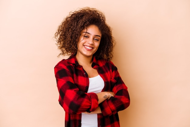 Foto jovem mulher afro-americana isolada na parede bege que se sente confiante, cruzando os braços com determinação.