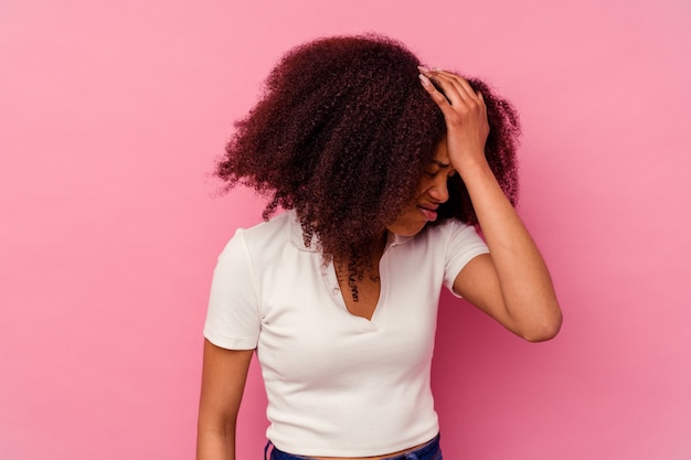 Jovem mulher afro-americana isolada na rosa esquecendo de algo, batendo na testa com a palma da mão e fechando os olhos.