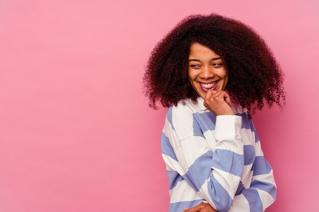 Jovem mulher afro-americana isolada na rosa relaxada pensando em algo olhando para um espaço de cópia.