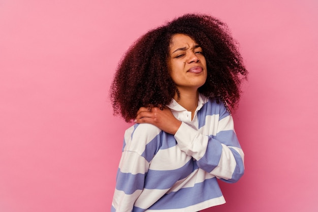 Jovem mulher afro-americana isolada na rosa, tendo uma dor no ombro.