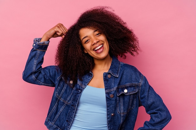 Jovem mulher afro-americana isolada na torcida rosa despreocupada e animada. Conceito de vitória.