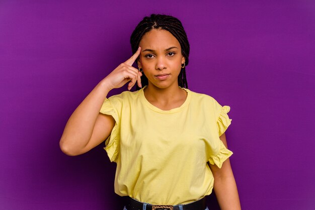 Jovem mulher afro-americana isolada no fundo amarelo Jovem mulher afro-americana isolada no fundo amarelo, apontando o templo com o dedo, pensando, focada em uma tarefa.