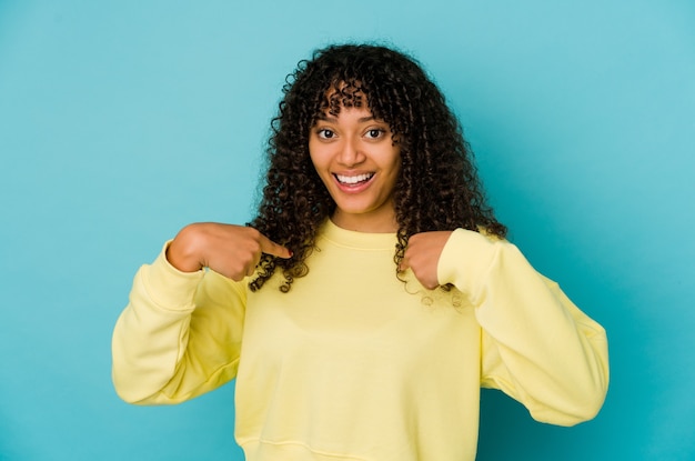 Jovem mulher afro-americana isolada surpresa apontando com o dedo, sorrindo amplamente.