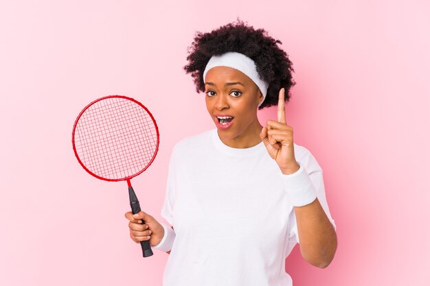 Jovem mulher afro-americana jogando badminton isolado, tendo uma ideia, o conceito de inspiração.