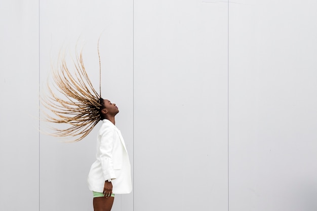 Jovem mulher afro-americana jogando o cabelo loiro comprido trançado para trás. Copie o espaço.