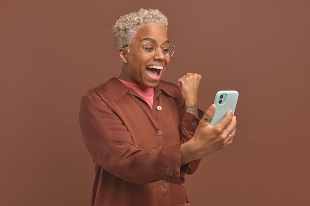 Jovem mulher afro-americana muito feliz assistindo transmissão de jogos esportivos no telefone