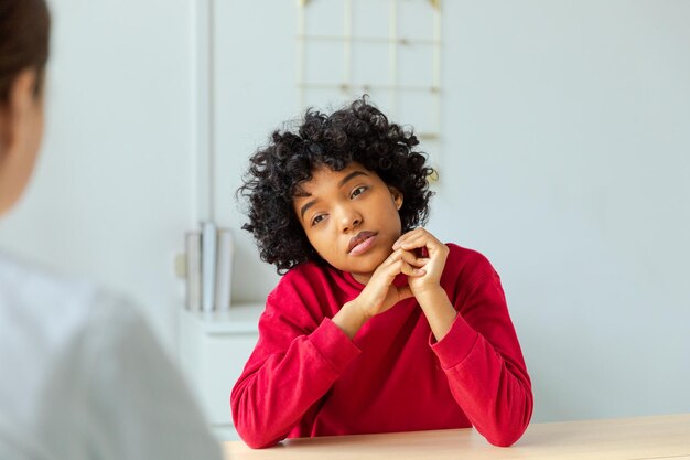 Foto jovem mulher afro-americana paciente e médica no consultório do médico menina paciente e médico têm