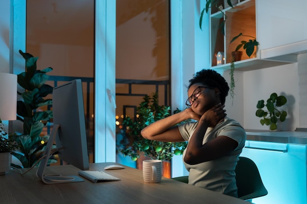 Jovem mulher afro-americana sobrecarregada de trabalho freelancer em óculos trabalhando até tarde em casa