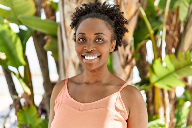 Jovem mulher afro-americana sorrindo feliz em um dia de verão