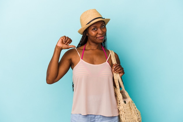 Jovem mulher afro-americana, vestindo roupas de verão, isoladas em fundo azul, sente-se orgulhosa e autoconfiante, exemplo a seguir.