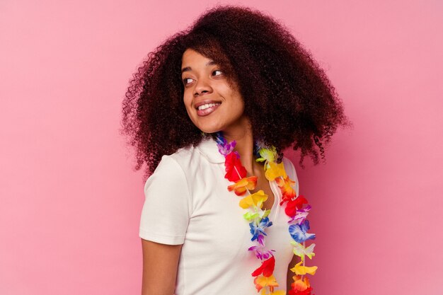 Foto jovem mulher afro-americana vestindo uma coisa havaiana parece de lado sorrindo, alegre e agradável.