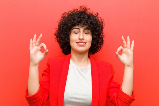 Jovem mulher afro bonita olhando concentrado e meditando, sentindo-se satisfeito e relaxado, pensando ou fazendo uma escolha