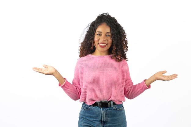 Jovem mulher afro com cabelo encaracolado aponta para o lado no espaço livre para promoção de texto e publicidade