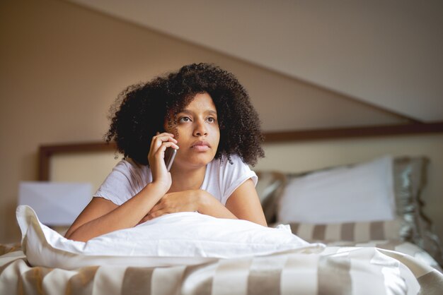 Jovem mulher afro falando no telefone inteligente.