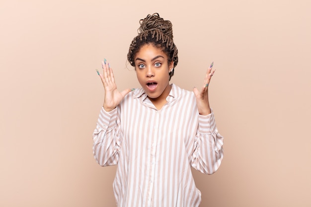 Jovem mulher afro parecendo chocada e surpresa