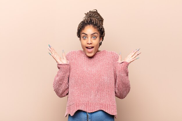 Jovem mulher afro parecendo orgulhosa, confiante e feliz, sorrindo e apontando para si mesma ou fazendo o primeiro sinal