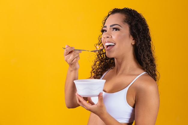 Jovem mulher afro saudável comendo salada de frutas.