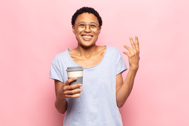 Jovem mulher afro se sentindo feliz, surpresa e alegre, sorrindo com atitude positiva, percebendo uma solução ou ideia