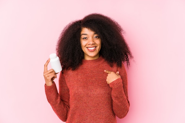 Jovem mulher afro, segurando um frasco de comprimidos de vitamina