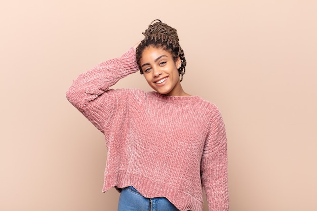 Jovem mulher afro sorrindo alegremente e comemorando, com os punhos cerrados e os braços cruzados, sentindo-se feliz e positiva