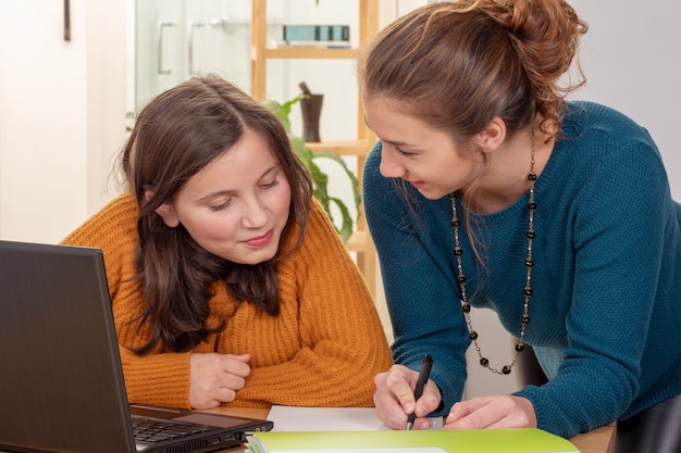 Jovem mulher ajuda uma menina adolescente com lição de casa