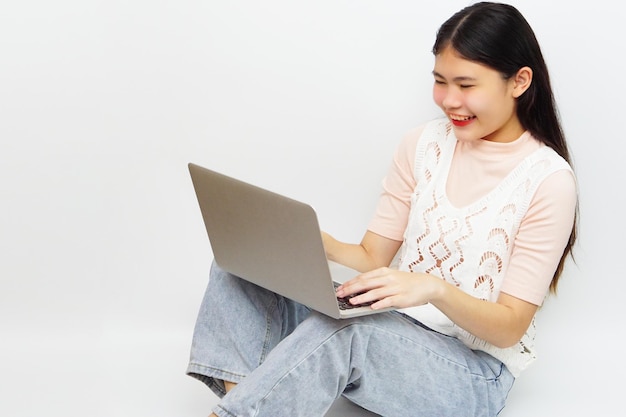 Jovem mulher alegre asiática sentada e usando laptop. Tecnologia e conceito de aprendizagem.
