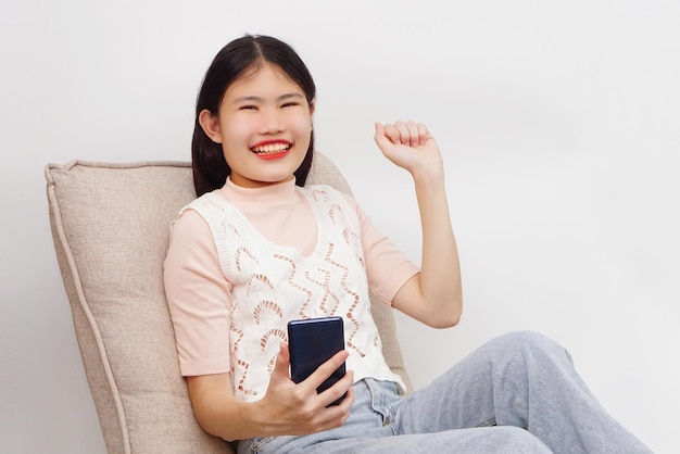 Jovem mulher alegre asiática sentada e usando smartphone. Conceito de tecnologia e estilo de vida.