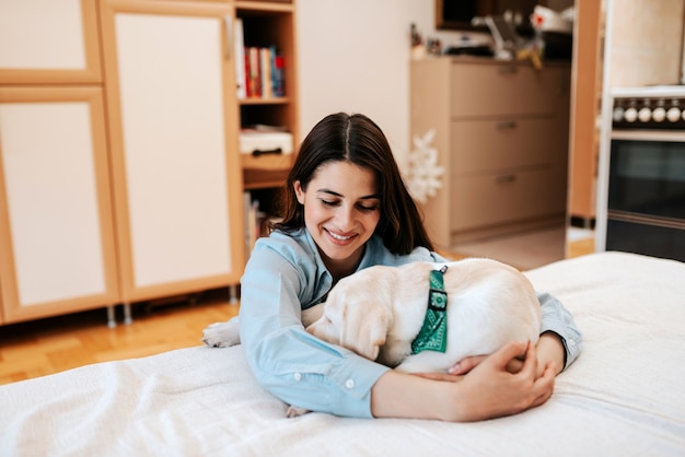 Jovem mulher alegre com o cão no apartamento.