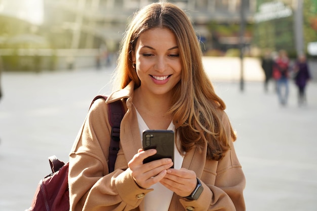 Jovem mulher sorrindo e rindo enquanto enviava mensagens de texto em um  telefone em casa mulher alegre conversando com seus amigos nas mídias  sociais navegando online e assistindo memes engraçados da internet