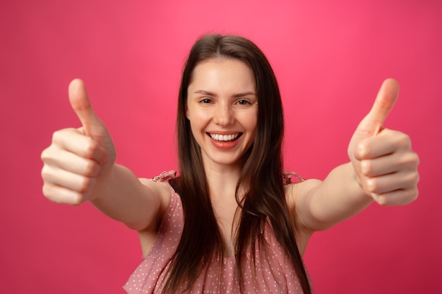 Jovem mulher alegre e feliz mostrando o polegar no estúdio