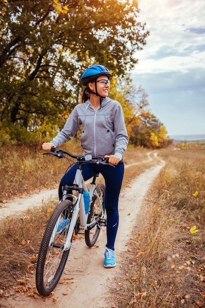 Jovem mulher andando de bicicleta no campo de outono