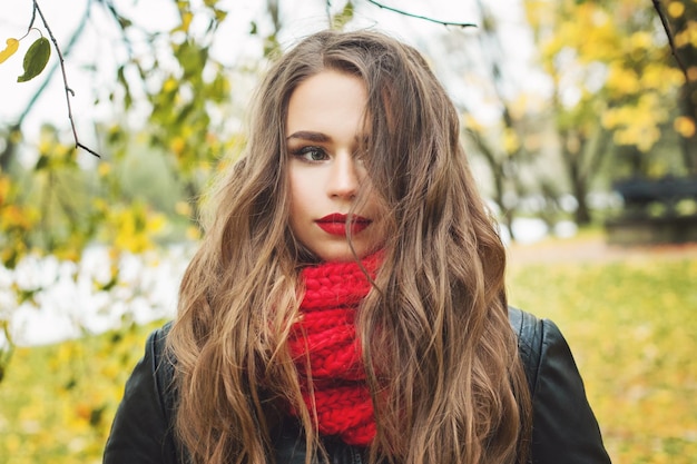 Jovem mulher ao ar livre no parque de outono Modelo feminino perfeito em cachecol vermelho de malha