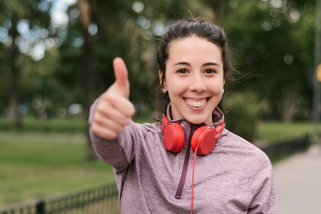 Jovem mulher aparecendo seus polegares após treino