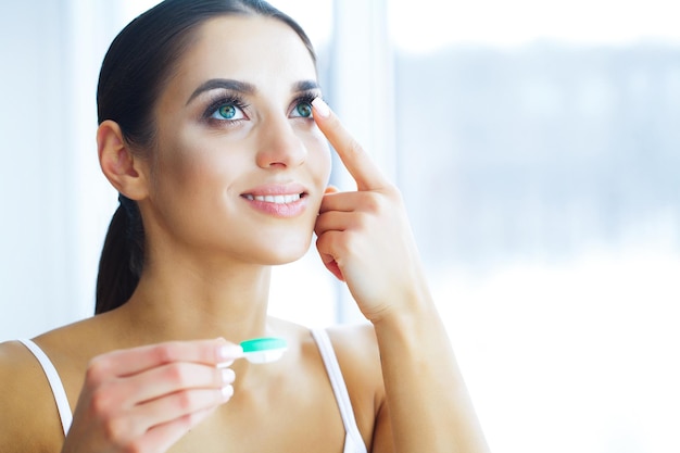 Jovem mulher aplicando lentes de contato