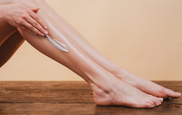 Jovem mulher aplicando loção corporal nas pernas creme cosmético na perna da mulher com pele limpa e macia aplicando m