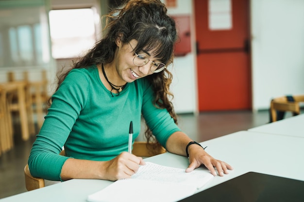 Jovem mulher aprendendo dentro da biblioteca na escola universitária