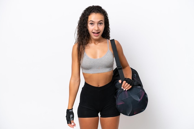 Jovem mulher árabe esportiva com bolsa esportiva isolada em fundo branco com expressão facial de surpresa