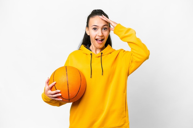 Jovem mulher árabe jogando basquete sobre fundo branco isolado com expressão de surpresa