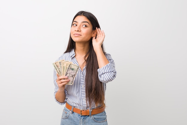 Jovem mulher árabe segurando dólares tentando ouvir uma fofoca.