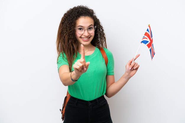 Jovem mulher árabe segurando uma bandeira do Reino Unido isolada no fundo branco mostrando e levantando um dedo