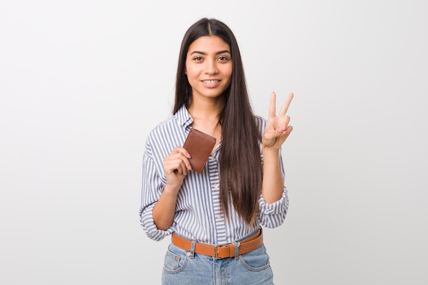 Jovem mulher árabe segurando uma carteira mostrando o número dois com os dedos