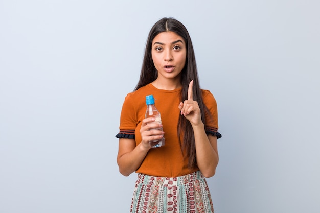 Jovem mulher árabe segurando uma garrafa de água, tendo uma ótima idéia, conceito de criatividade.