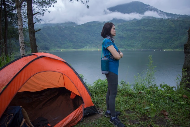 Jovem mulher asiática acampando ou fazendo um piquenique no lago da floresta.